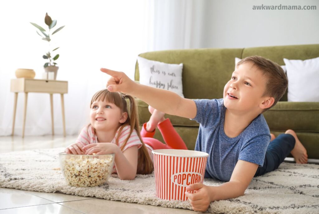 Two children lying on the floor watching a movie together during a calm family wind-down routine