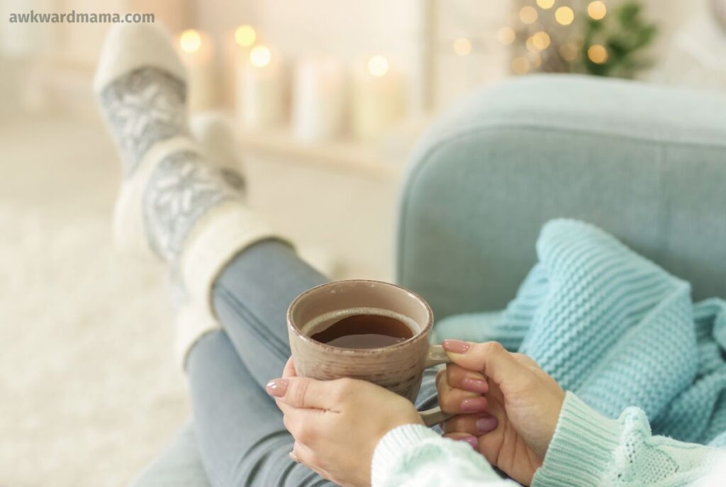Mom relaxing with coffee in cozy socks as part of a simple self-care habit