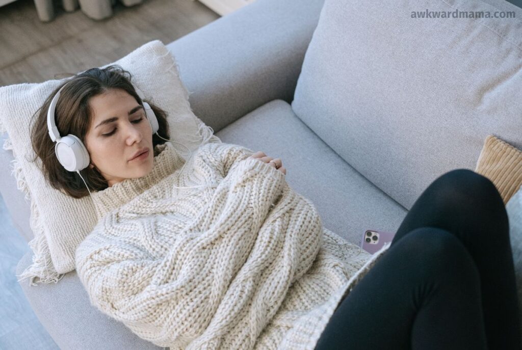 Woman lying on couch with headphones enjoying a quiet self-care break